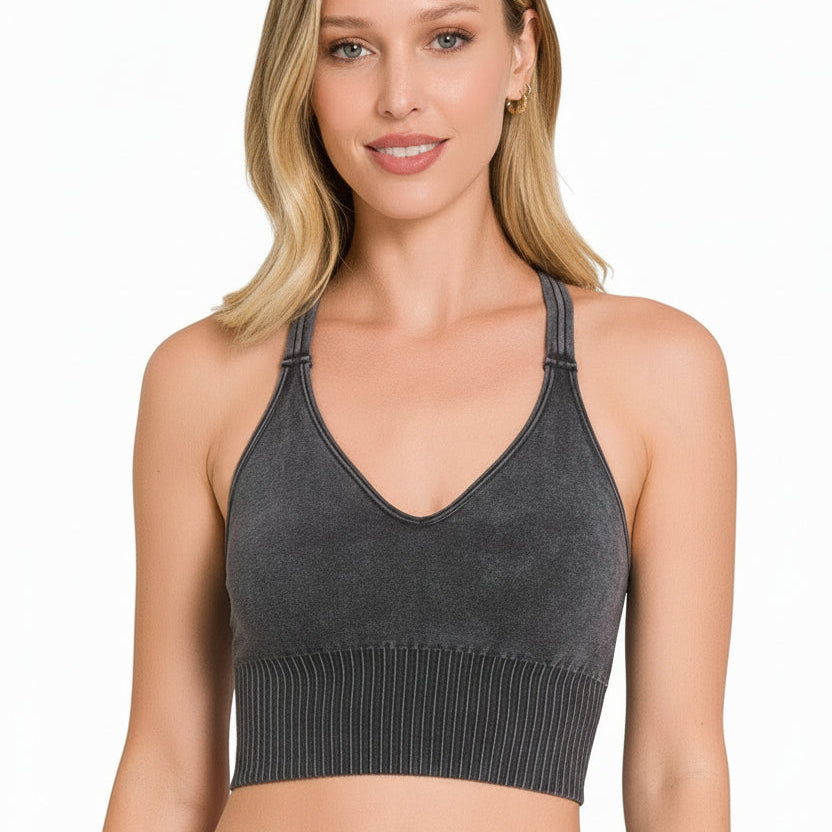 Woman wearing a gray knit crop top and blue jeans on a white background